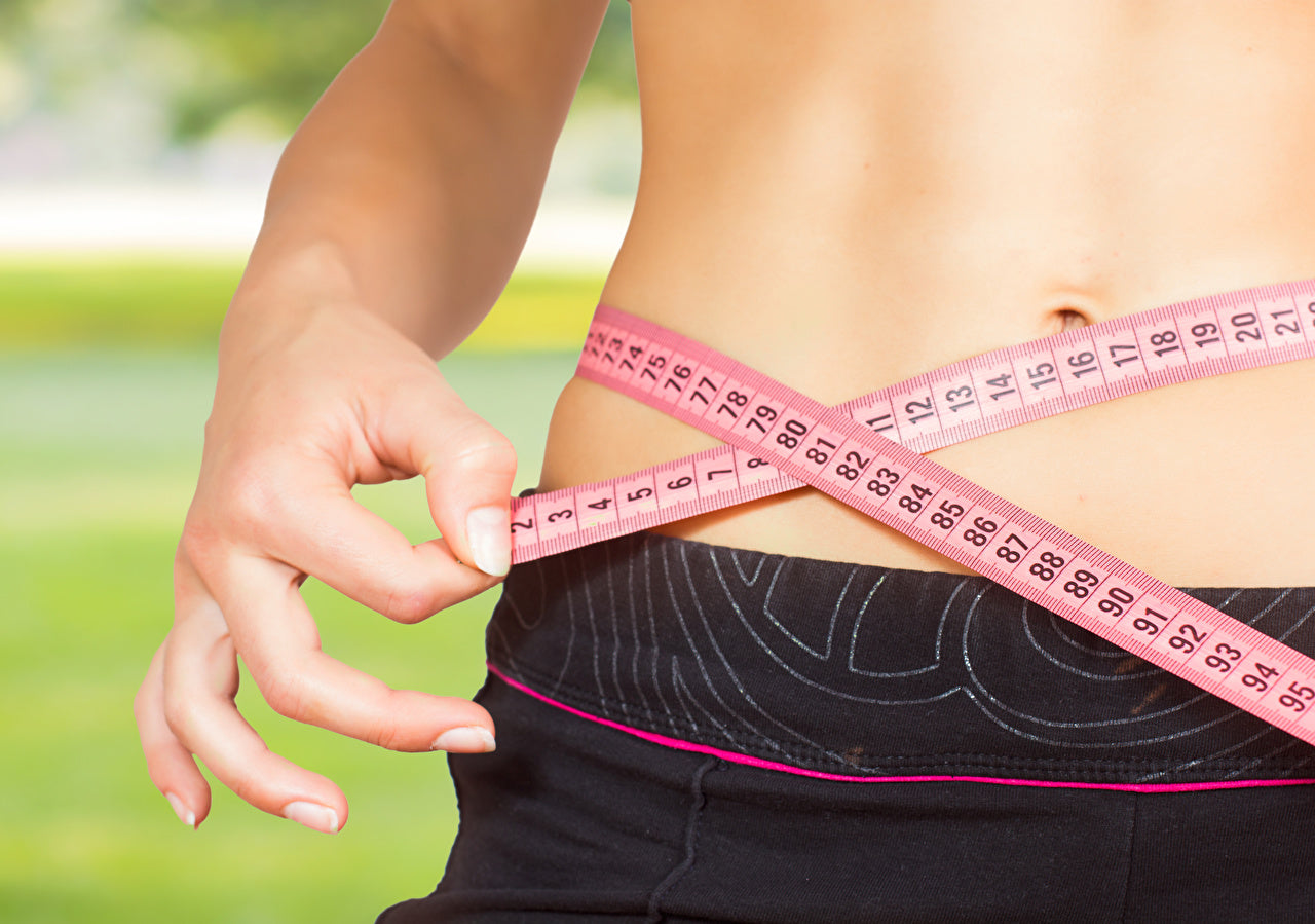 Ventre de femme musclé avec qui mesure le tour de taille avec un ruban 