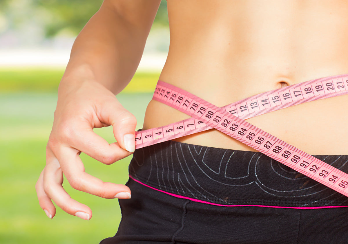 Ventre de femme musclé avec qui mesure le tour de taille avec un ruban 
