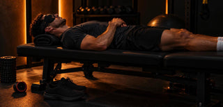 Sportif allongé sur un banc de salle sombre, masque de sommeil sur les yeux, pendant une courte sieste de récupération