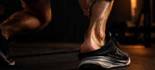 Gros plan sur le tendon d'Achille d'un coureur, chaussure de running à moitié retirée, main posée sur le mollet