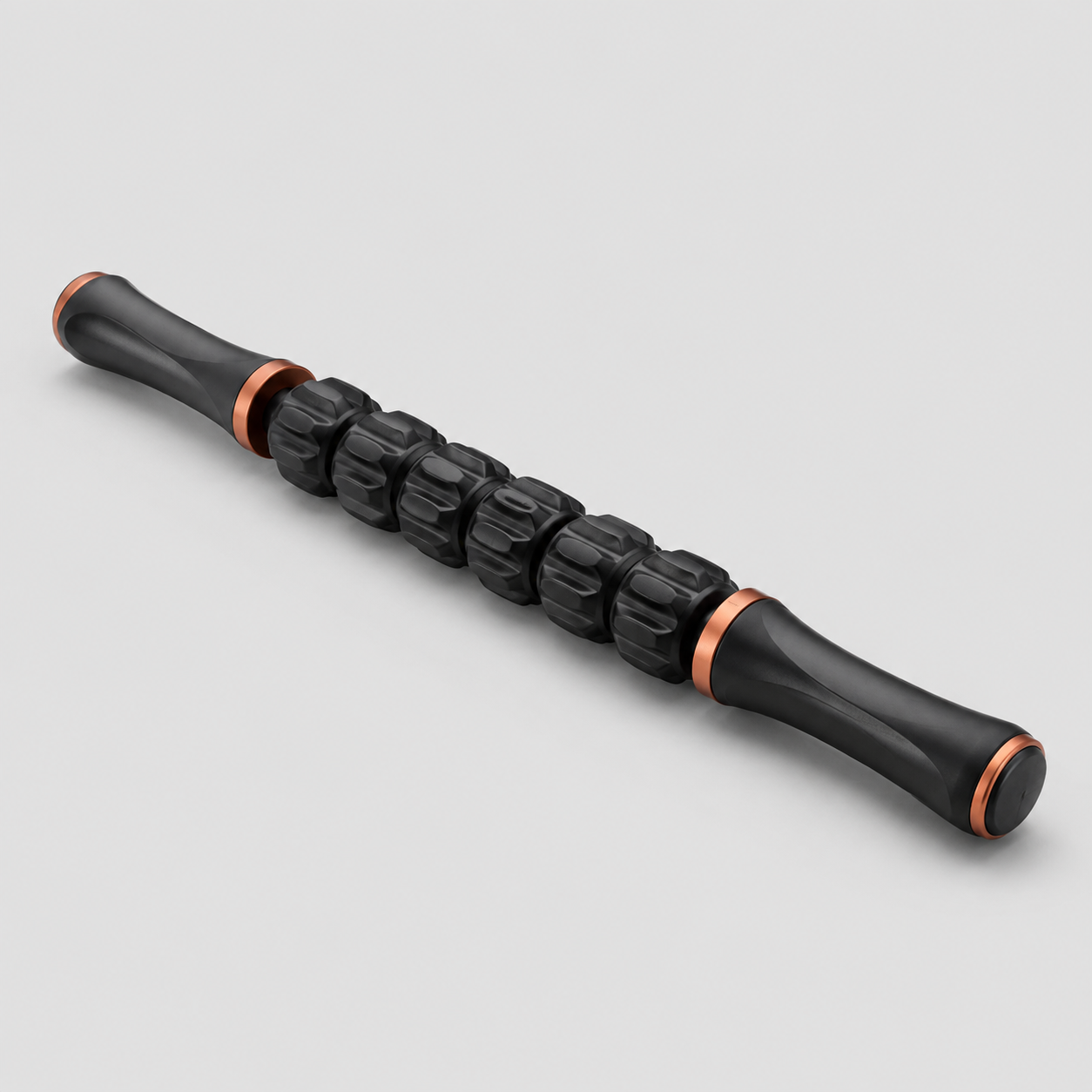Bâton de massage Shapebox Stick noir et cuivre, rouleaux texturés, fond studio gris clair